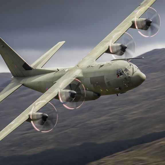 Photo of green airplane mid flight, possibly turning to the right.