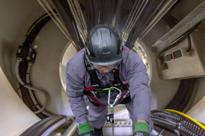 Interior of a modern wind turbine mast. A metal hull is installed with big bundles of cables ladder and safety features.