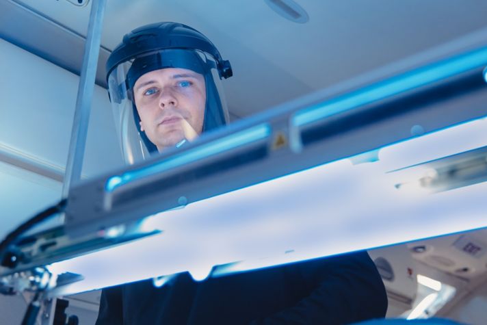 Honeywell UV Treatment System in airplane cabin aisle with arms extended over seating