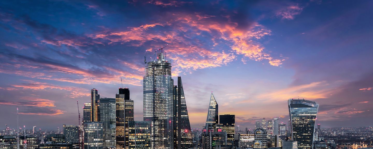 The City of London, financial district of the Metropole, just after sunset with illuminated buildings and cloudy sky, United Kingdom
