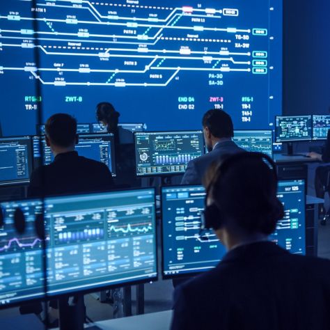 Team of Professional Computer Data Science Engineers Work on Desktops with Screens Showing Charts, Graphs, Infographics, Technical Neural Data and Statistics. Low Key Control and Monitoring Room.