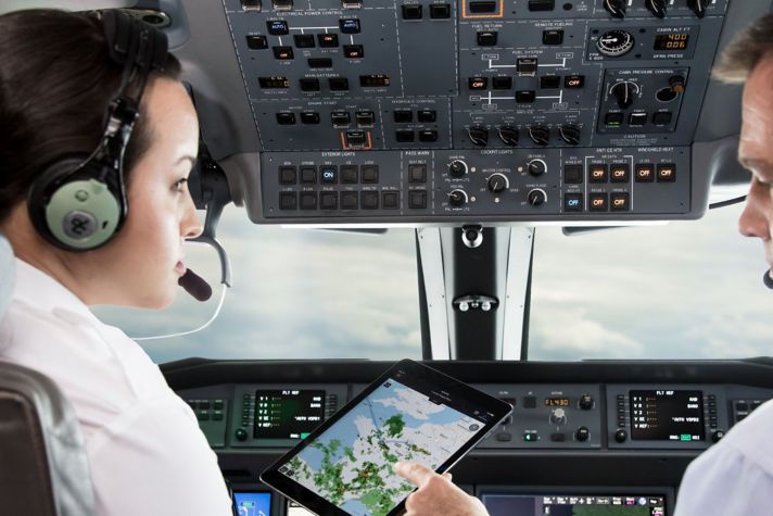 Two pilots analyze a weather screen in the airplane cockpit