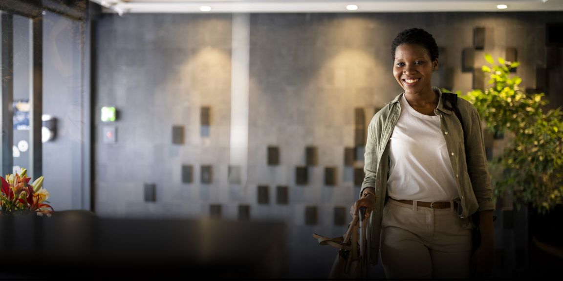Confident young woman arriving in hotel reception