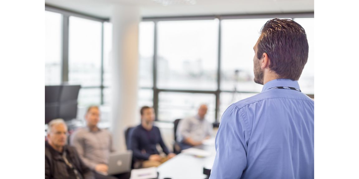 Business man making a presentation at office. Business executive delivering a presentation to his colleagues during meeting or in-house business training, explaining business plans to his employees. 