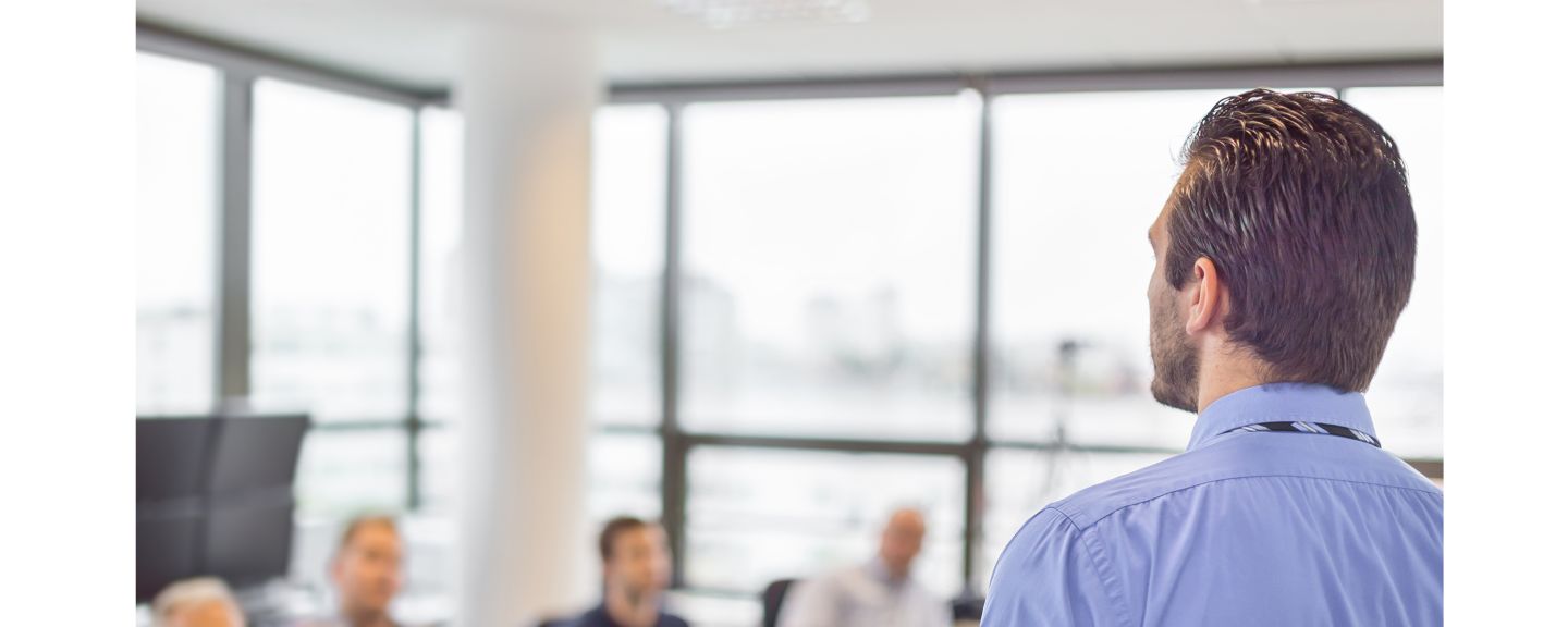 Business man making a presentation at office. Business executive delivering a presentation to his colleagues during meeting or in-house business training, explaining business plans to his employees. 