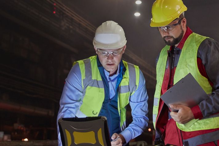 Two engineers examining charts on a laptop 
