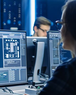 Smart Female IT Programer Working on Desktop Computer in Data Center System Control Room. Team of Young Professionals Doing Code Programming