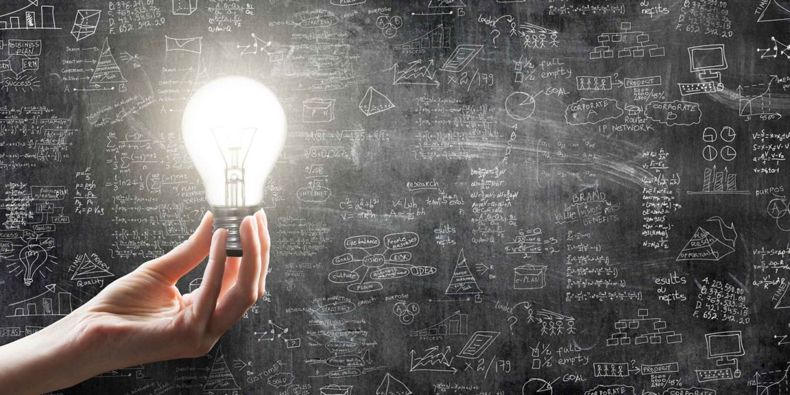Hand Holding A Light Bulb In Front Of A Math Formulas