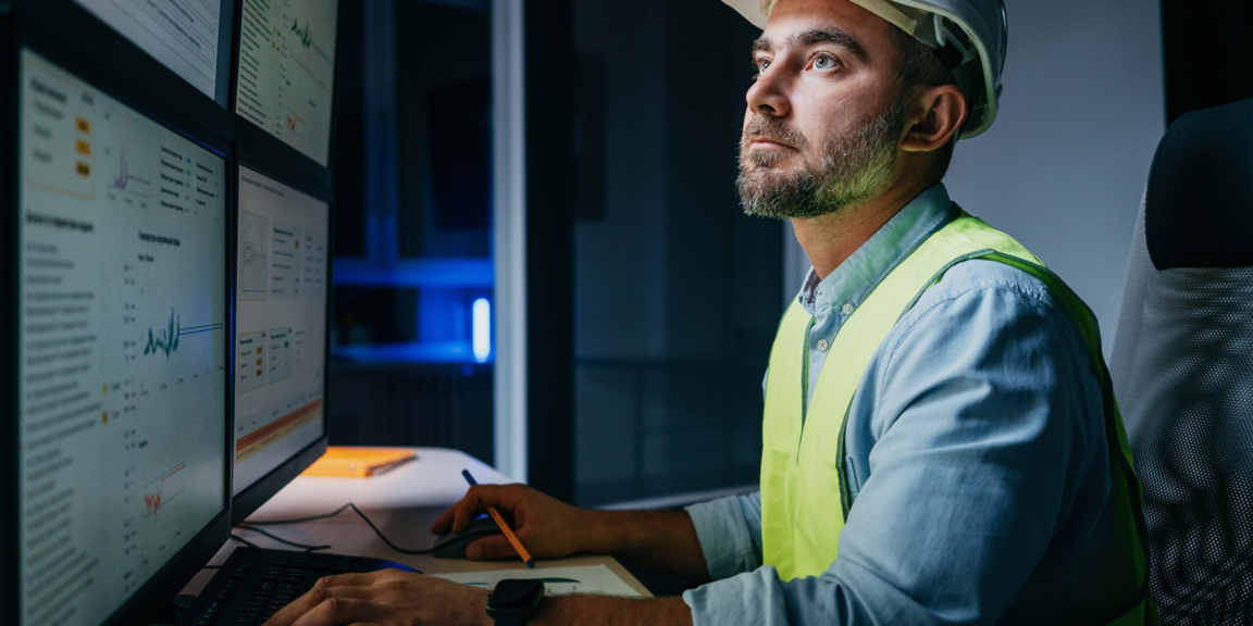 Bearded operator of factory control industry process using monitors. Engineer follow on production line