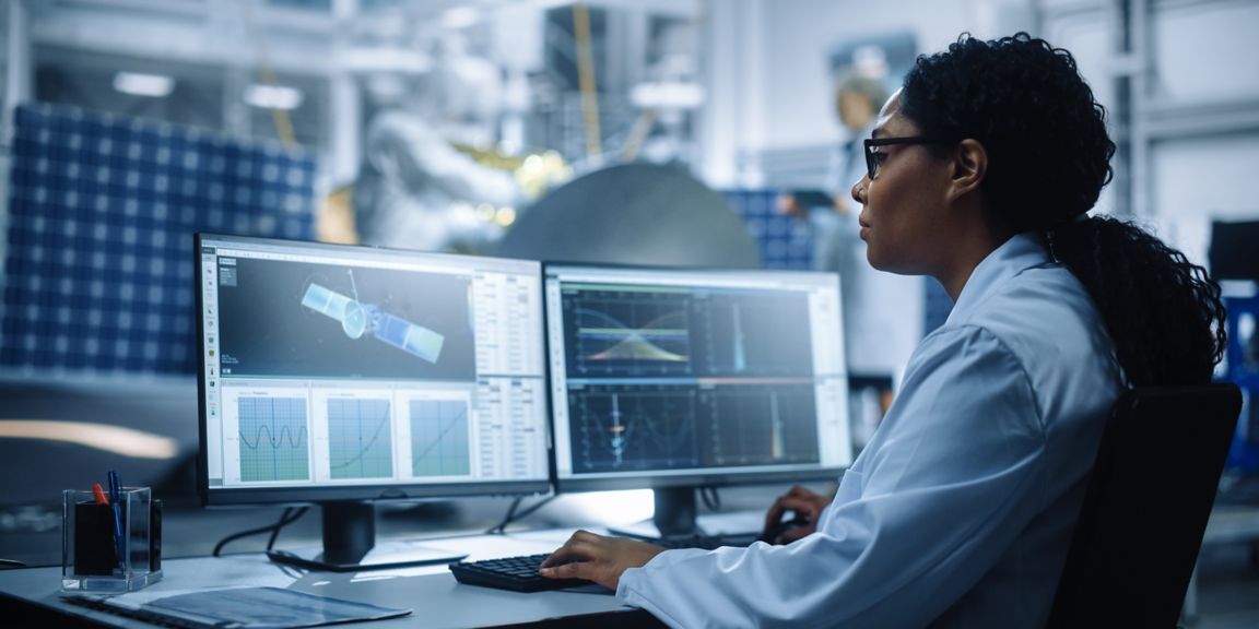 Female Engineer uses Computer to Analyse Satellite, Calculate Orbital Trajectory Tracking. Aerospace Agency International Space Mission: Scientists Working on Spacecraft Construction. Over Shoulder