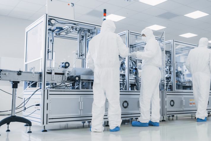 In the Manufacturing Facility Team of Scientist Wearing Sterile Protective Coverall Set's up / Programs Modern Industrial 3D Printer, High Precision Manufacture of Semiconductors under Process.