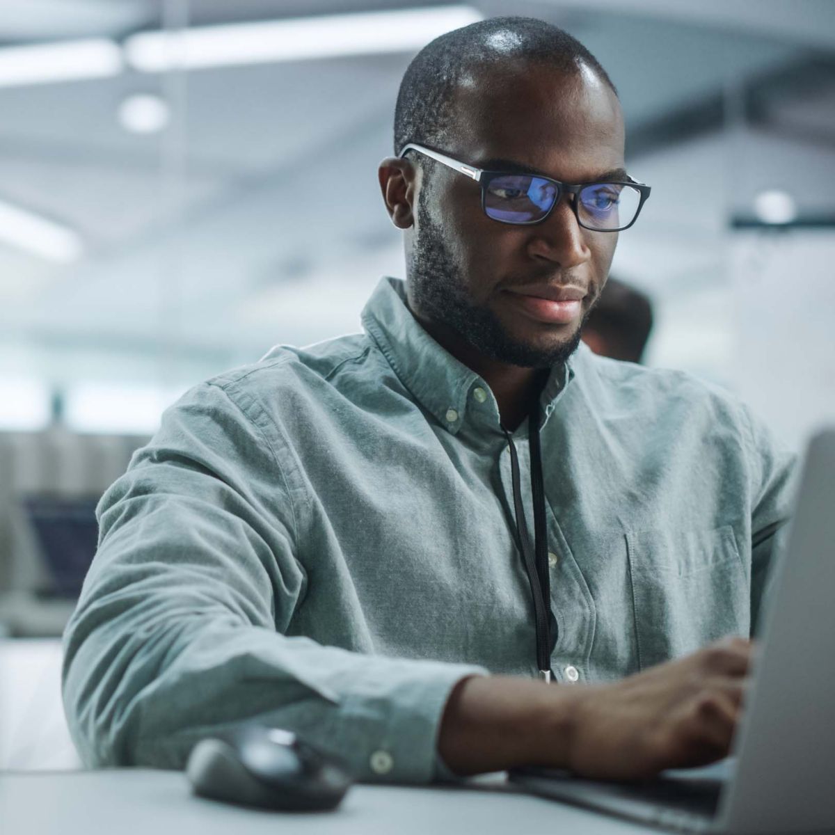 Modern Office: Portrait of Motivated Black IT Programmer Working on Laptop Computer. Male Specialist Create Website, Software Engineer Develop App, Program, Video Game. Stress Free Inclusive Space