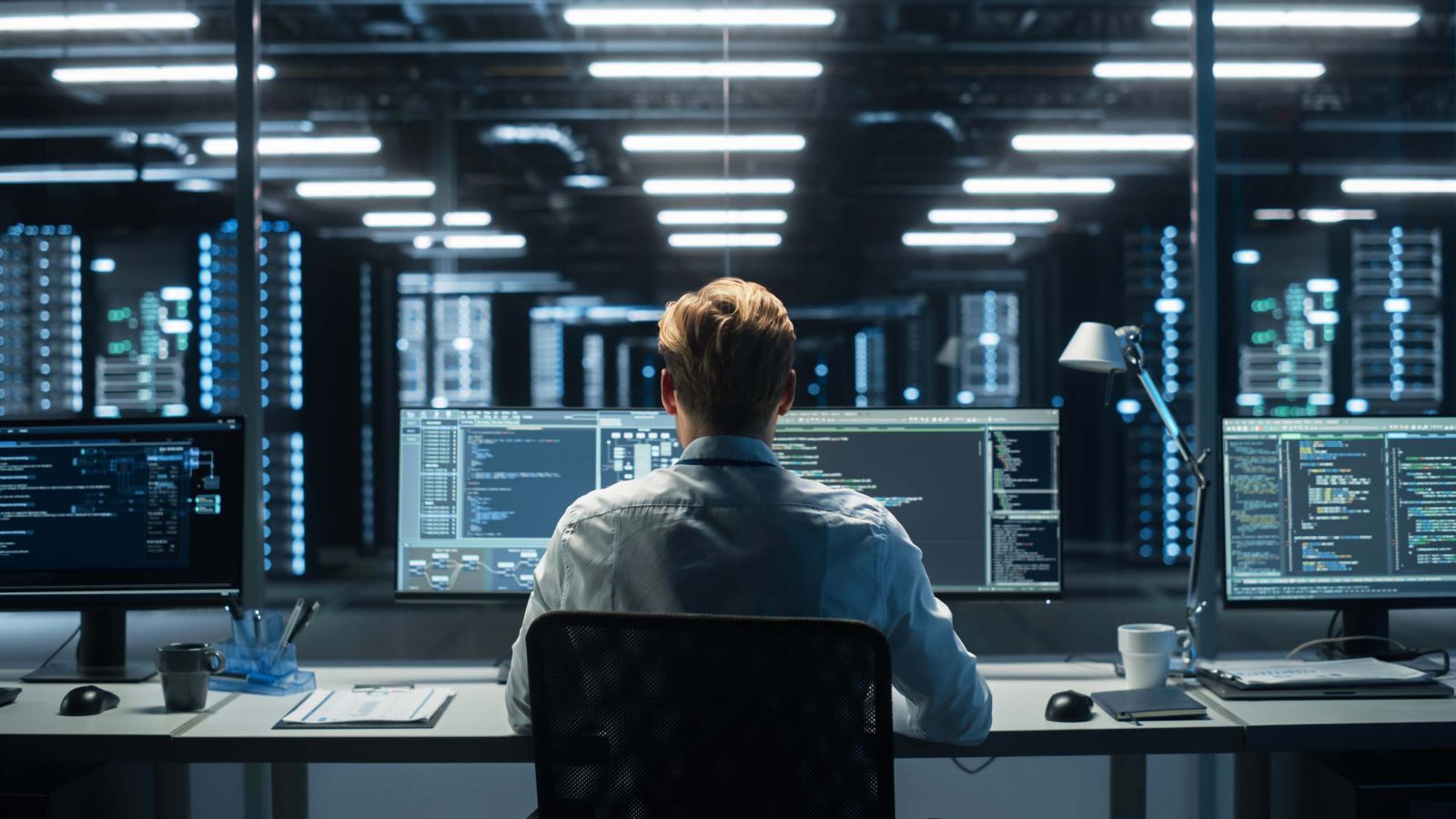 In the System Control Room Technical Operator Sits and Monitors Various Activities Showing on Multiple Displays with Graphics. Responsibility for Information Security in the Company Concept