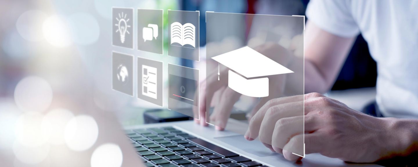 a conceptual representation of digital education or e-learning. It shows a person using a laptop with an overlay of educational icons, including a graduation cap, a lightbulb, and books.