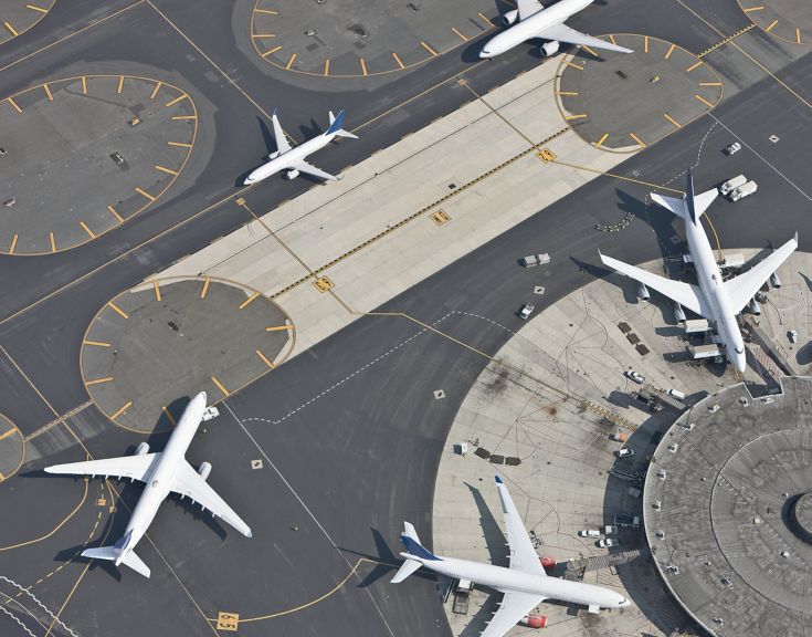 An overhead view captures multiple commercial aircraft navigating the complex taxiways and terminal apron of a busy international airport.