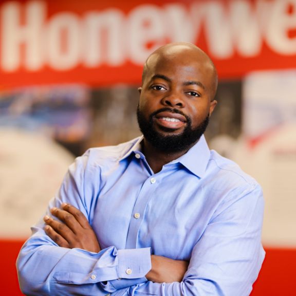 Professional portrait of Ajibola Fowowe, captured in a clean studio setting with the Honeywell logo as a background.