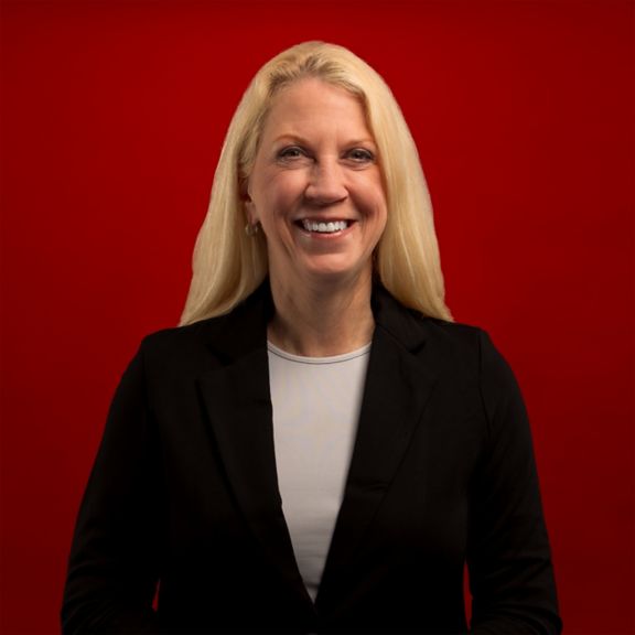 Professional portrait of Anne Madden, captured against a bold red background.