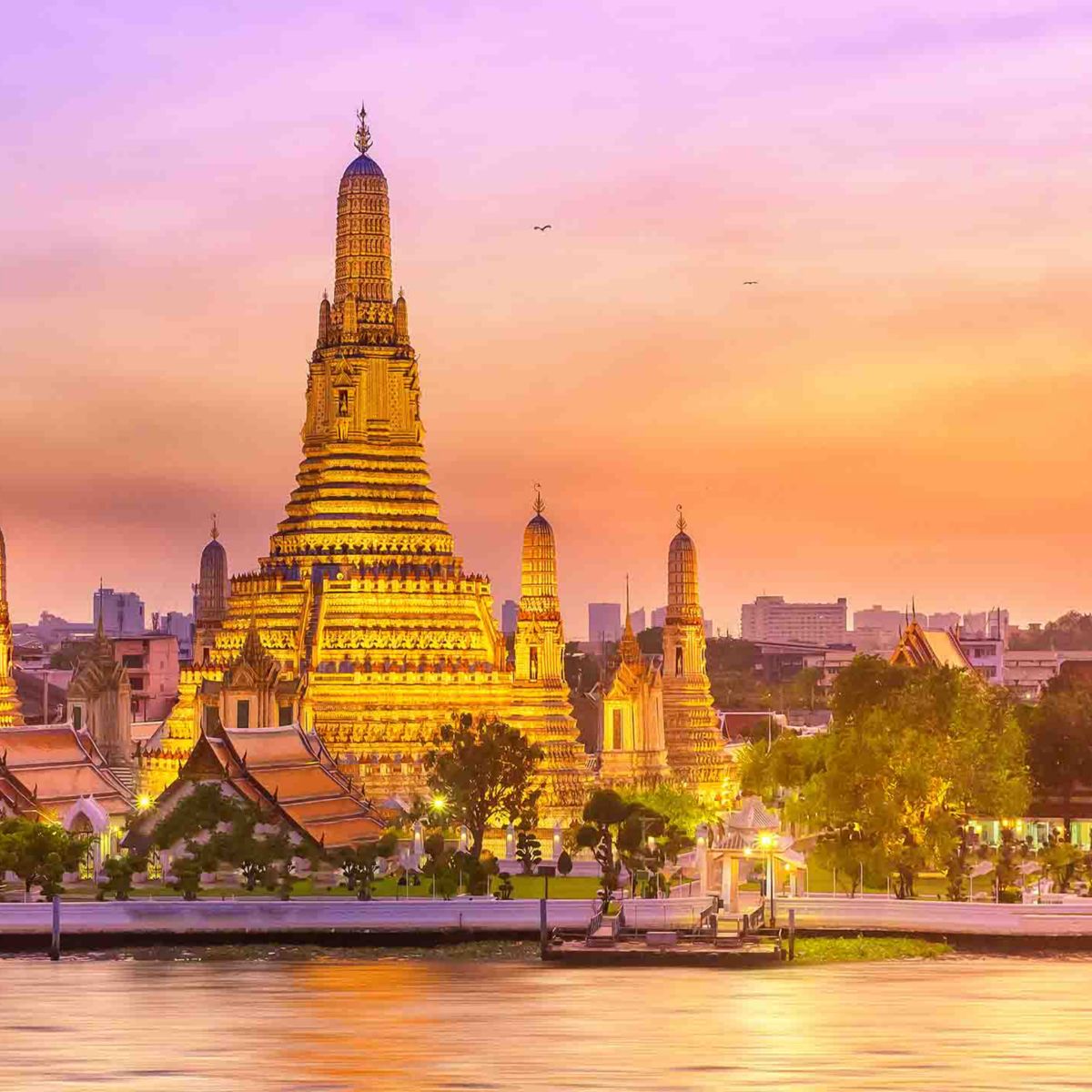 Captivating view of Wat Arun at sunset, highlighting its intricate architecture against a pastel sky, with the Chao Phraya River in the foreground.