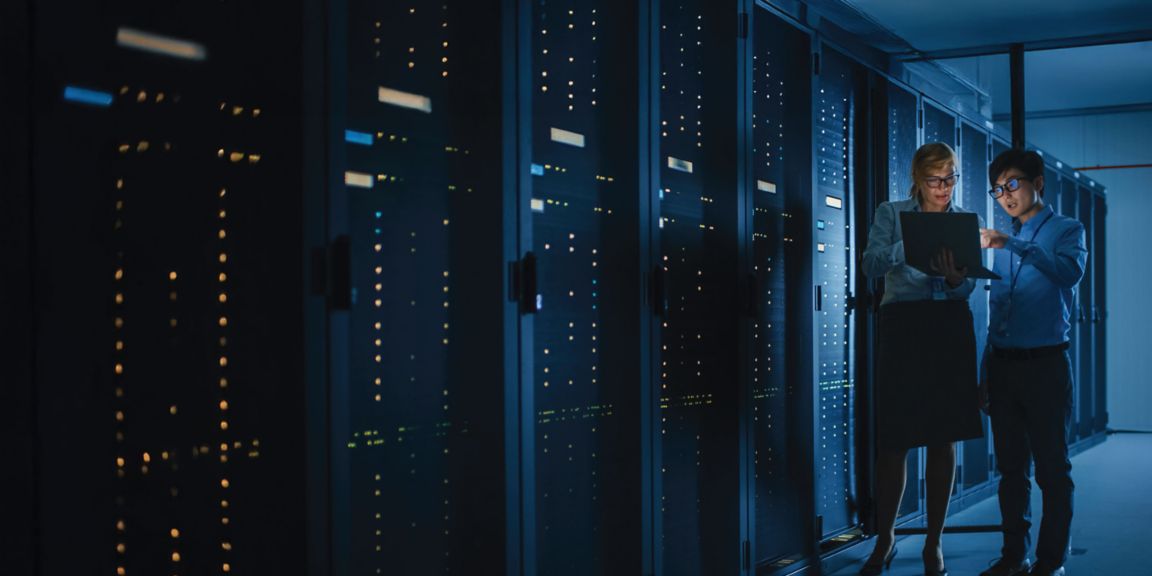 Two individuals working in server room with equipment racks