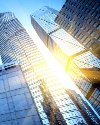A stunning view of modern skyscrapers in an urban cityscape, captured from a low angle with sunlight reflecting off the glass surfaces. The image showcases the architectural beauty and grandeur of tall buildings against a clear blue sky.
