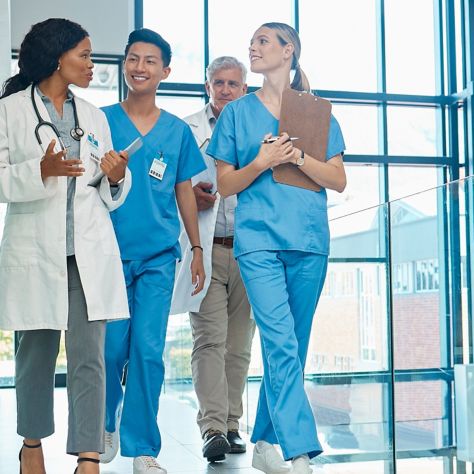 Doctors and nurses walk together in bright hospital hallway.