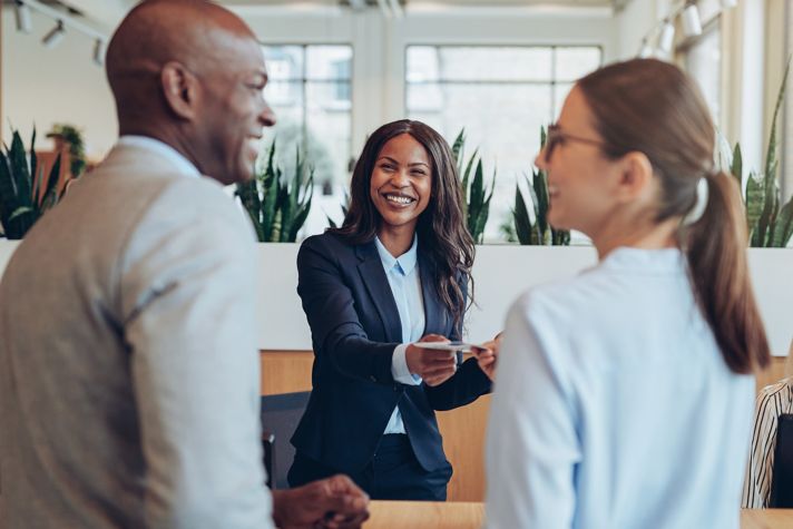 Guests interacting with staff in a contemporary hotel lobby, showcasing smooth check‑in service and a welcoming atmosphere.