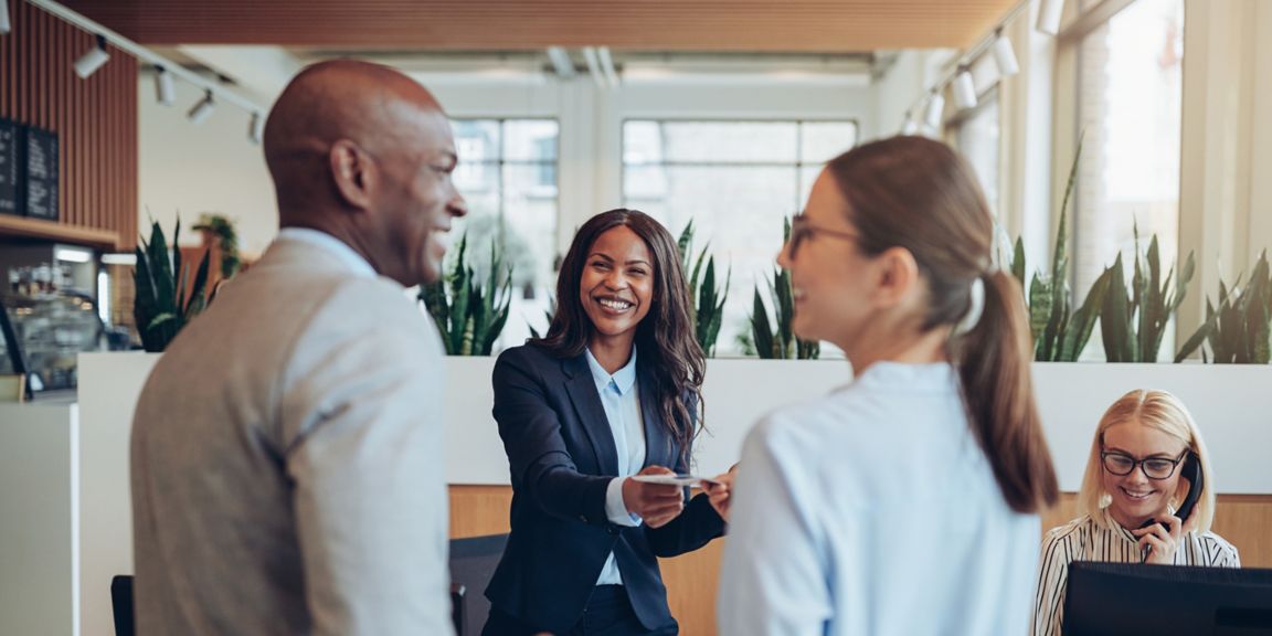 Four colleagues interact in bright, contemporary office work setting.