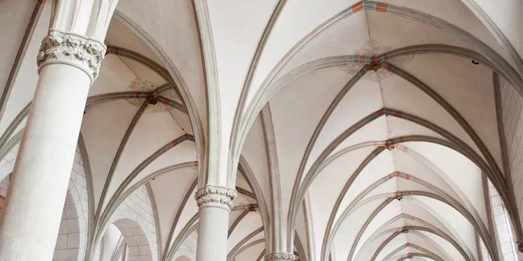 Explore the breathtaking architecture of a Gothic cathedral interior featuring intricate ribbed vaults, elegant columns, and detailed stone carvings. This image captures the grandeur and beauty of historical church design.