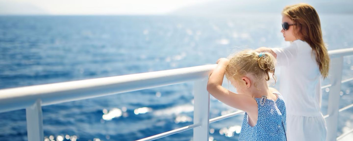 Onity two young girls looking over ship railing at the water