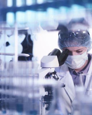 Female microbiologist studying coronavirus with microscope. Fighting with pandemic