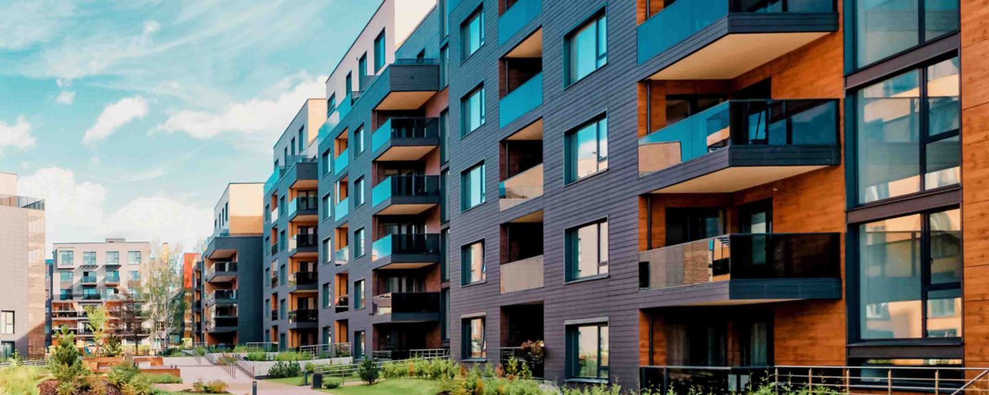 Modern apartment buildings featuring contemporary architecture, balconies, and landscaped green spaces in a vibrant urban residential area.