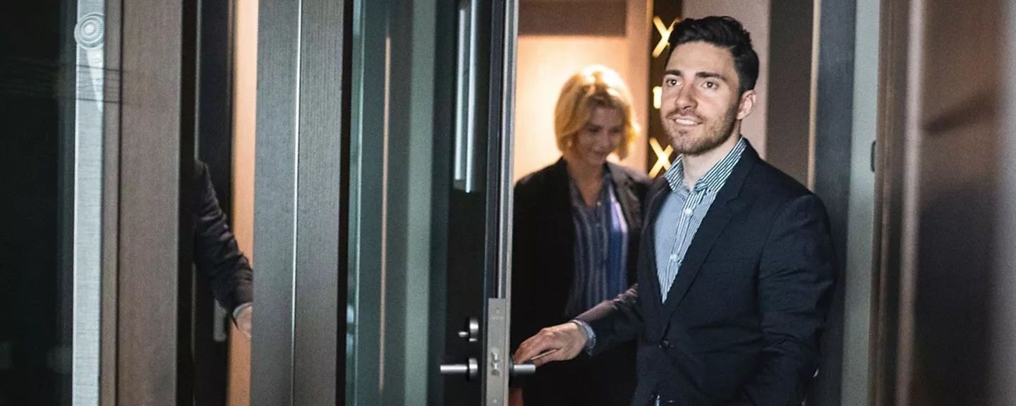 Man and woman entering a hotel room with bags