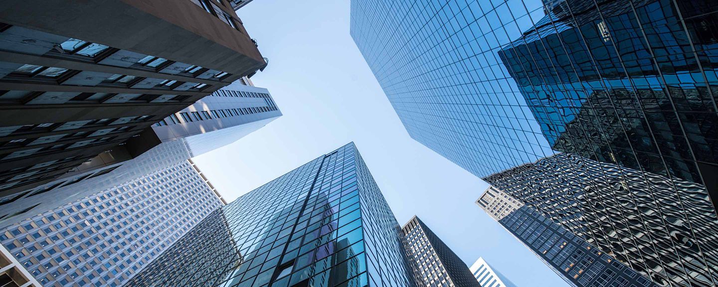 Reflective glass buildings rise high into the blue sky.