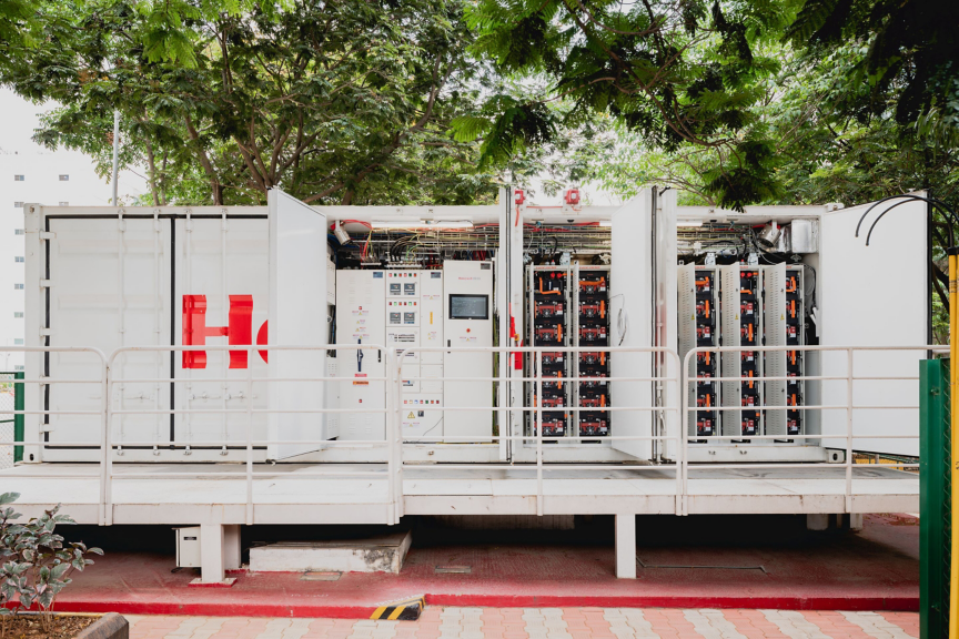 A modern battery storage container with open doors, revealing internal systems and battery packs.