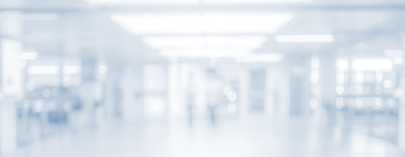 An empty hospital corridor appears softly blurred beneath bright ceiling lights.
