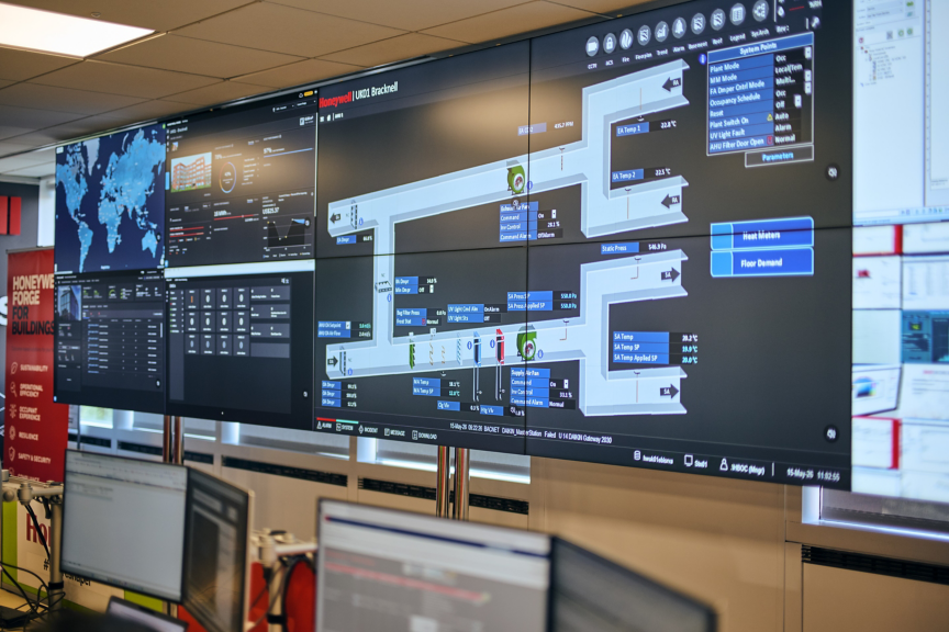 Advanced control room with large screens displaying building management system dashboards and real time performance data.
