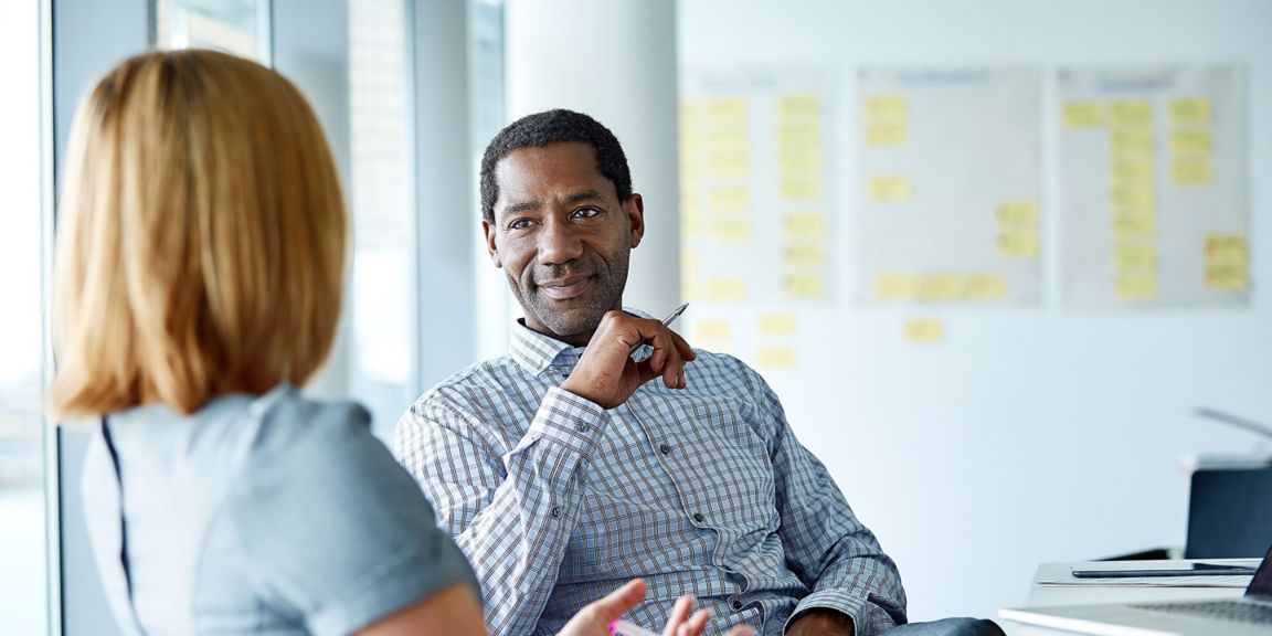 Two colleagues engage in conversation during a meeting, fostering collaboration in a modern office space.