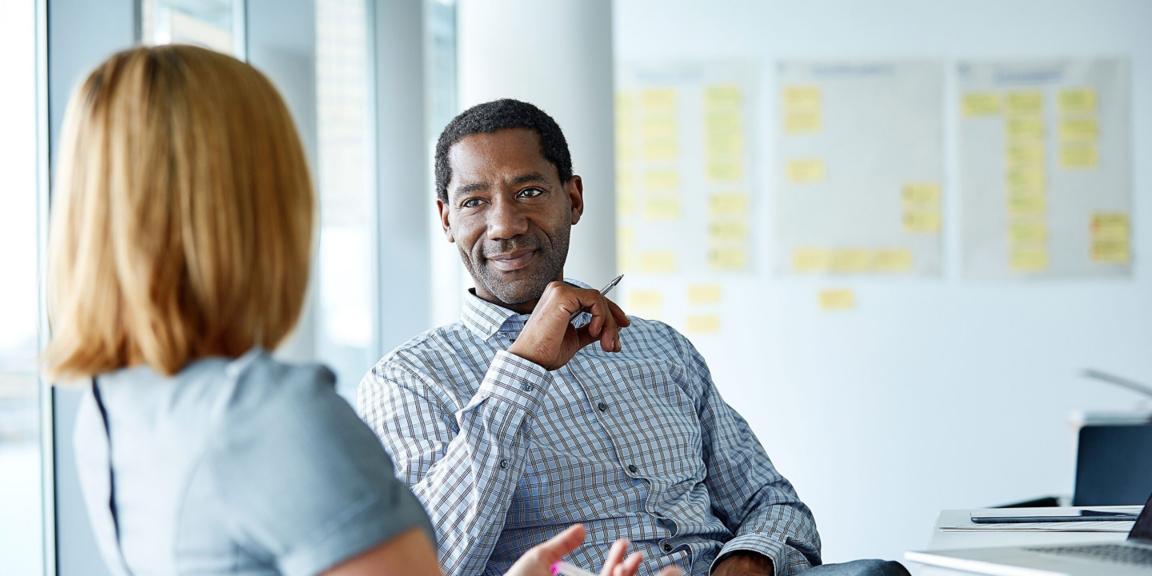Two colleagues engage in conversation during a meeting, fostering collaboration in a modern office space.
