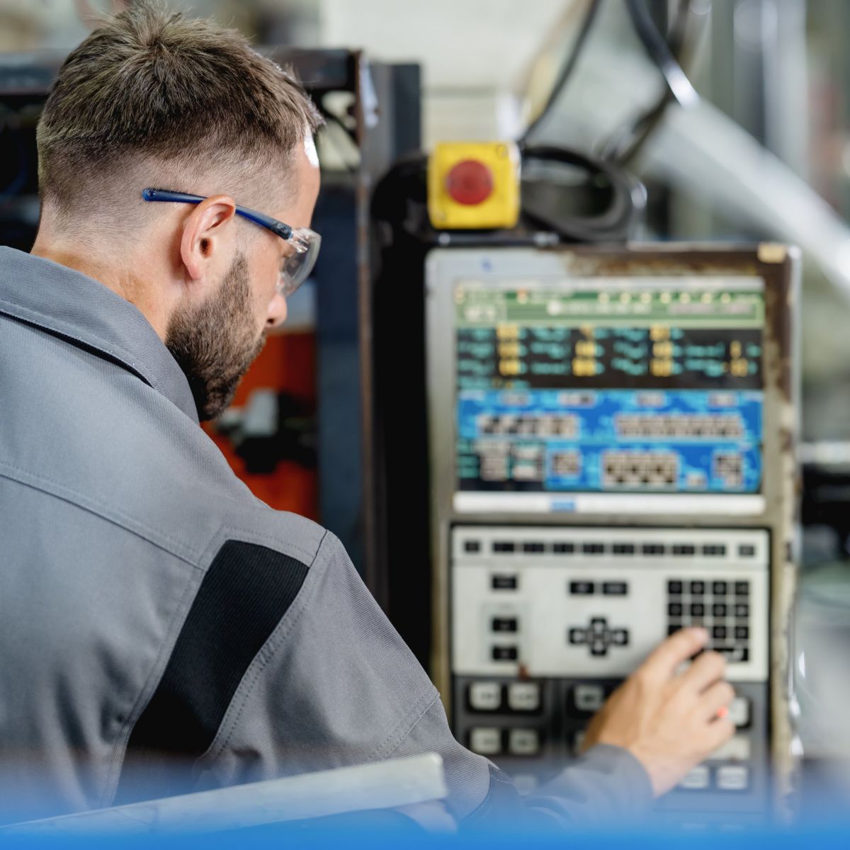 A professional technician operating a CNC machine console in a modern manufacturing facility.