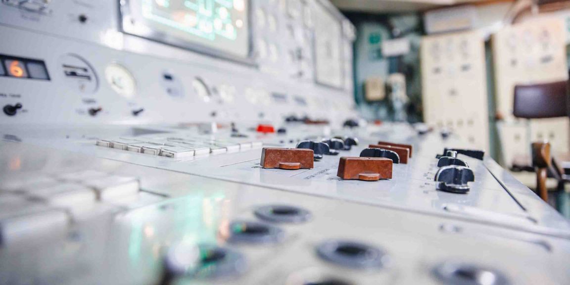 Close-up of a control room panel featuring various knobs and gauges, highlighting operational controls and measurements.