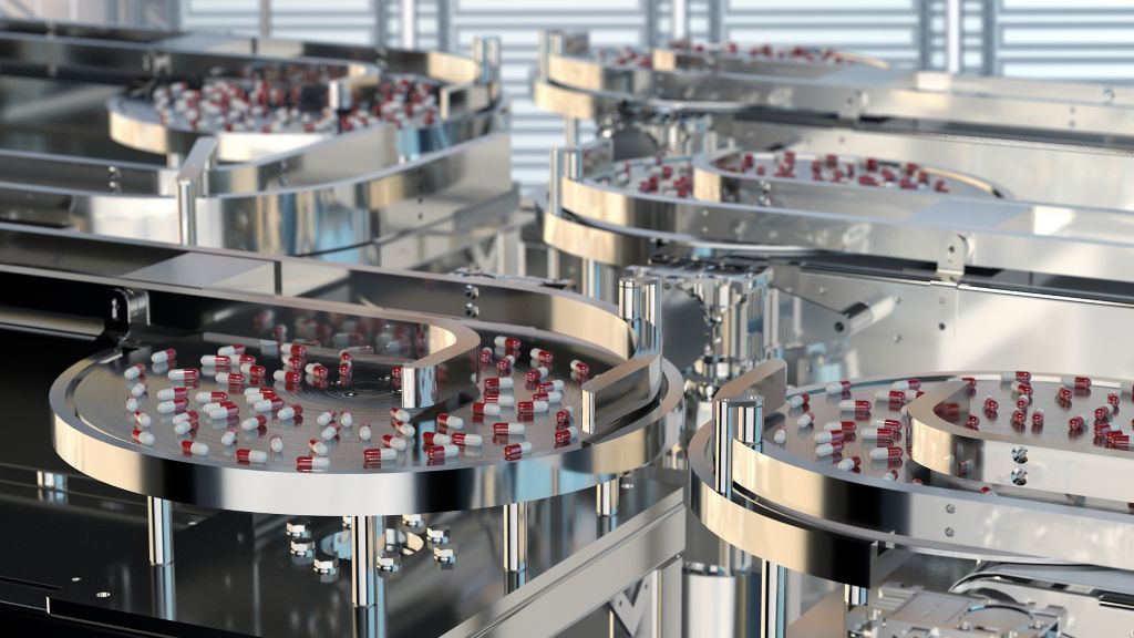 High-tech manufacturing environment featuring circular conveyor systems sorting red and white capsules. The stainless steel machinery highlights automation in pharmaceutical production.