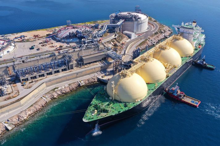 Liquified Natural Gas tanker anchored in small gas terminal island with tanks