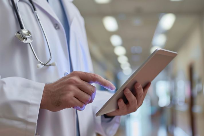 Doctor with Stethoscope using tablet for remote monitoring to check status of patient