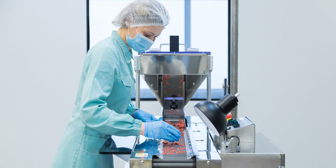 A technician in protective clothing manages equipment in a life science lab, focusing on precise handling of materials in a sterile environment.
