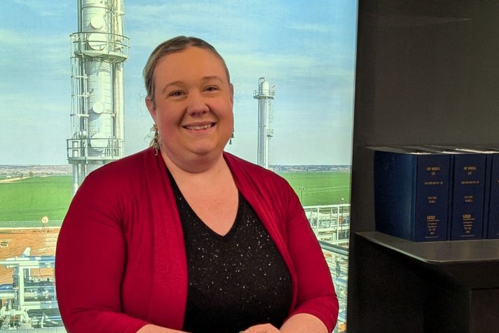 Christina Jackson smiles in front of a Honeywell UOP background.