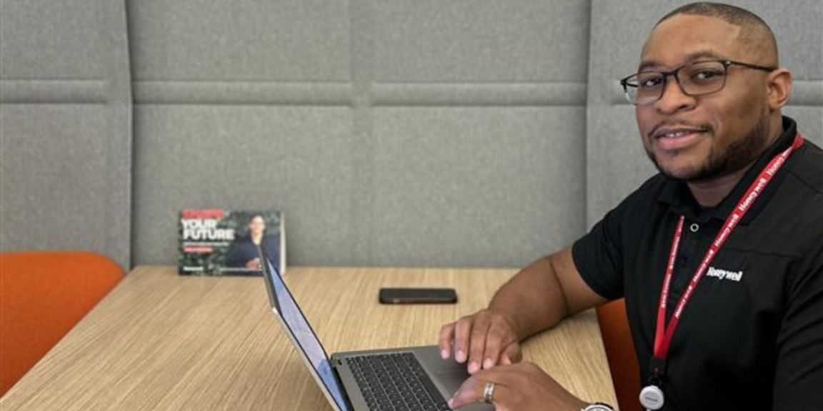 Honeywell employee Jeremy Smith smiles with a laptop open in an office setting.