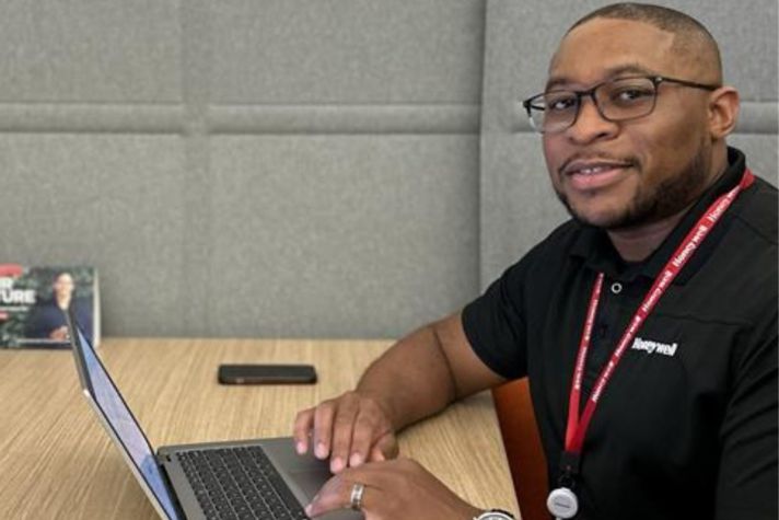 Honeywell employee Jeremy Smith smiles with a laptop open in an office setting.