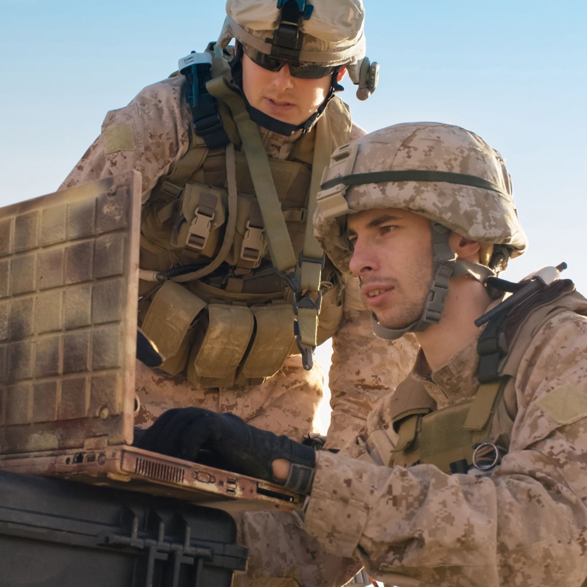 Soldiers dressed in desert camouflage over computer