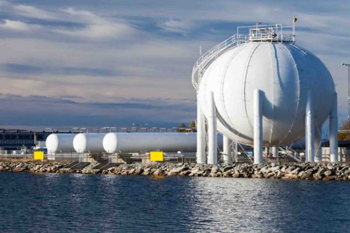 A gas storage facility featuring spherical tanks and cylindrical containers along a waterfront.