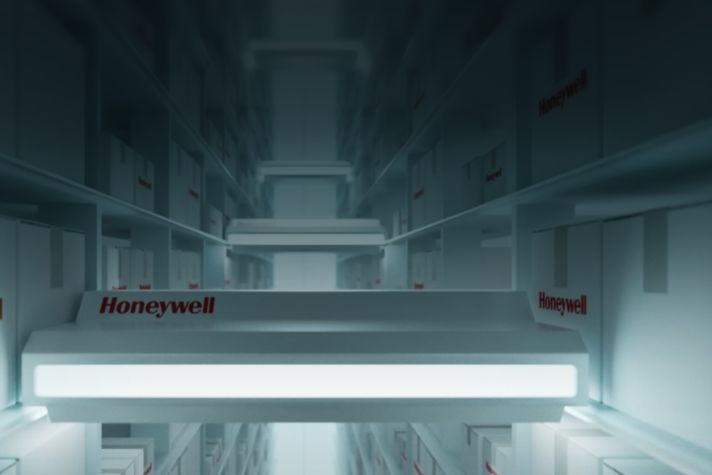 A dimly lit warehouse aisle showcasing organized white boxes with the Honeywell logo prominently displayed, creating a futuristic atmosphere.